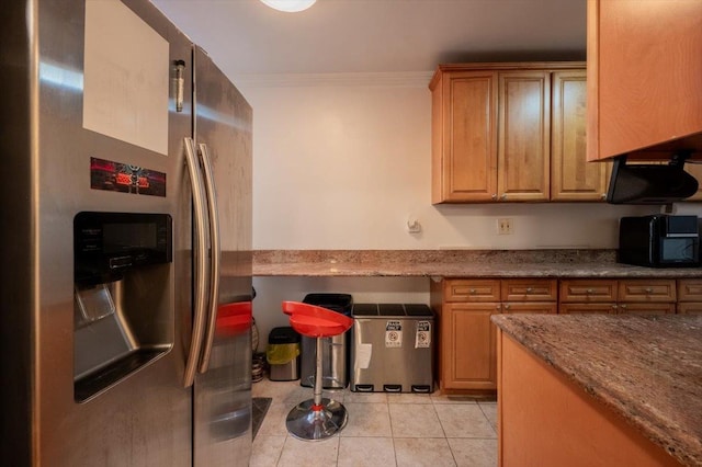 kitchen with light tile patterned floors, light stone counters, stainless steel fridge with ice dispenser, and crown molding