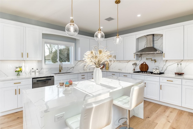 kitchen with white cabinets, a kitchen island, wall chimney range hood, stainless steel appliances, and a breakfast bar