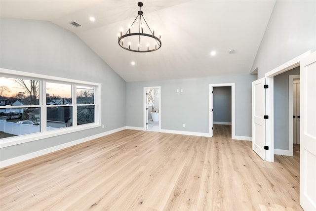 unfurnished living room with lofted ceiling, an inviting chandelier, and light hardwood / wood-style floors