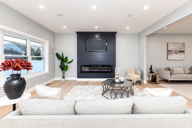 living room with light wood-type flooring and a large fireplace