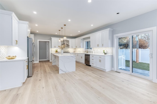 kitchen with white cabinetry, stainless steel appliances, a center island, hanging light fixtures, and sink