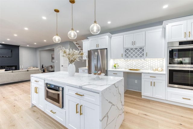 kitchen with decorative backsplash, white cabinetry, stainless steel appliances, and hanging light fixtures