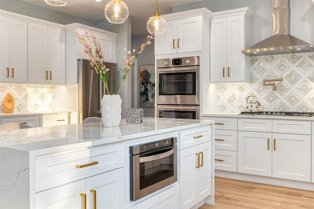 kitchen featuring tasteful backsplash, white cabinets, wall chimney exhaust hood, and stainless steel appliances