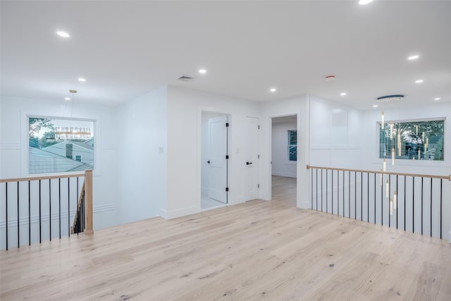 empty room with a chandelier and light wood-type flooring