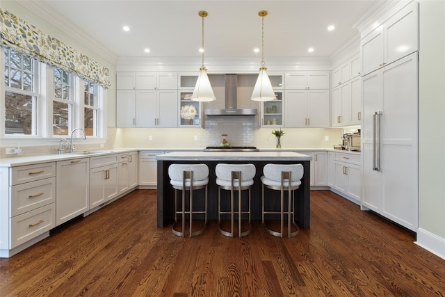 kitchen with dark wood-type flooring, wall chimney exhaust hood, white cabinets, and a center island