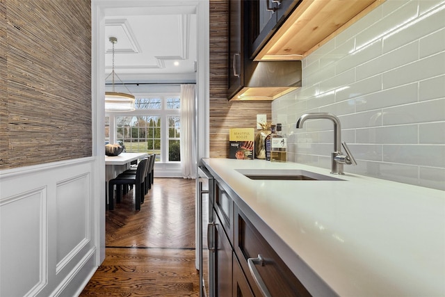 kitchen with decorative backsplash, dark brown cabinets, hanging light fixtures, and sink