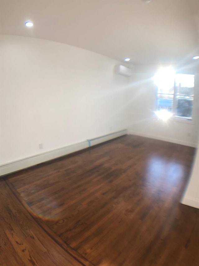 unfurnished room featuring a baseboard heating unit and dark hardwood / wood-style flooring