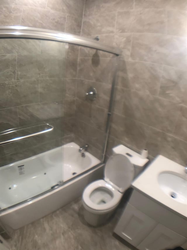 full bathroom with enclosed tub / shower combo, vanity, and toilet