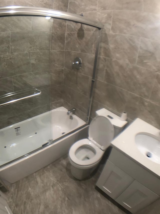 full bathroom featuring toilet, vanity, and shower / bath combination with glass door