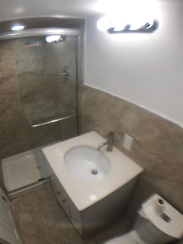 bathroom featuring a shower with shower door and vanity