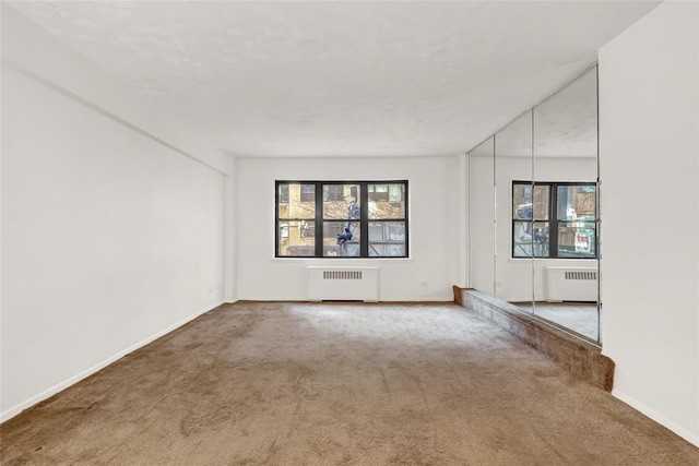 carpeted spare room featuring radiator heating unit