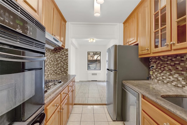 kitchen featuring light stone counters, radiator, appliances with stainless steel finishes, and decorative backsplash