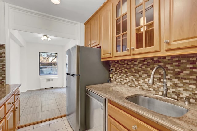 kitchen featuring dishwasher, sink, radiator, light stone countertops, and decorative backsplash