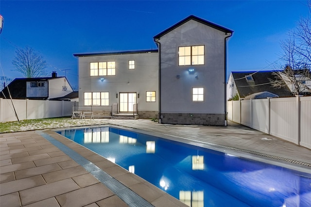 rear view of house with a fenced in pool and a patio