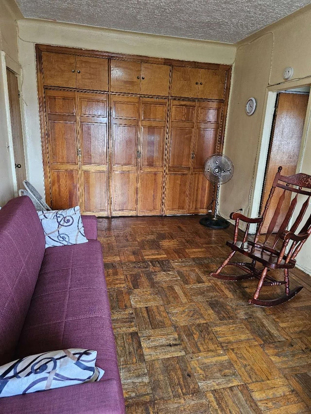 living area with a textured ceiling and dark parquet flooring