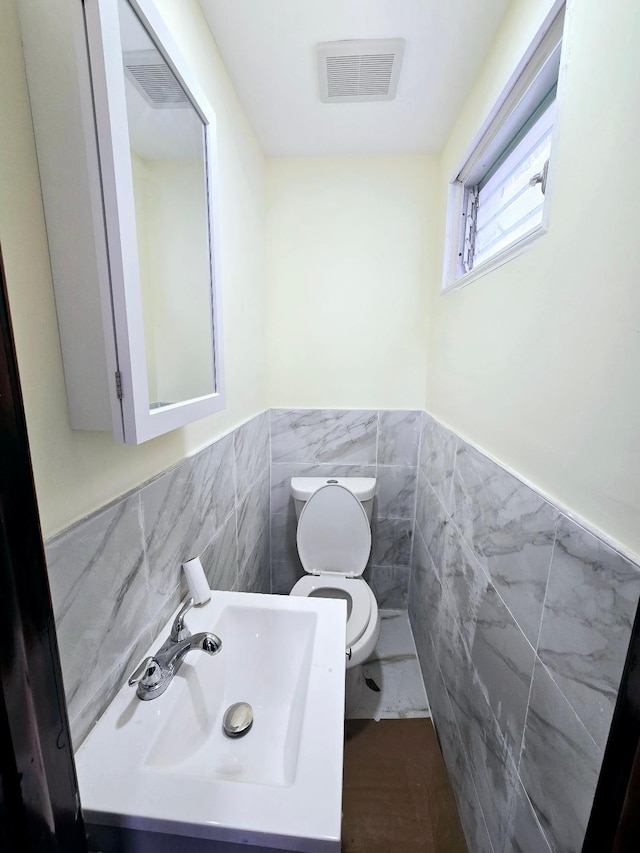 bathroom featuring toilet, tile walls, tile patterned floors, and sink