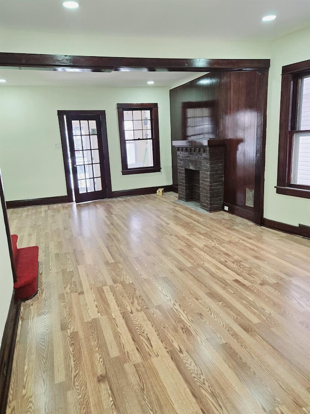 unfurnished living room with light wood-type flooring and a brick fireplace