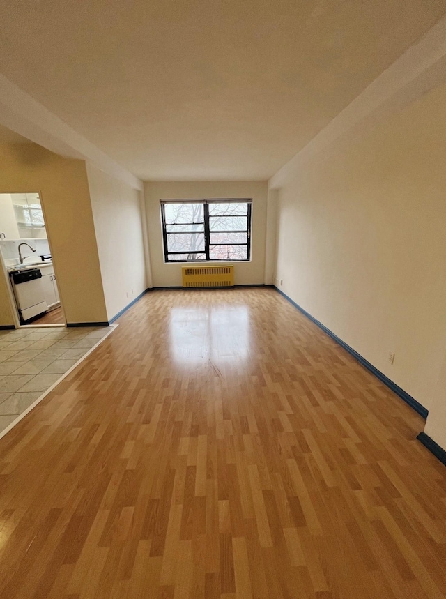 unfurnished room with radiator heating unit and light hardwood / wood-style floors