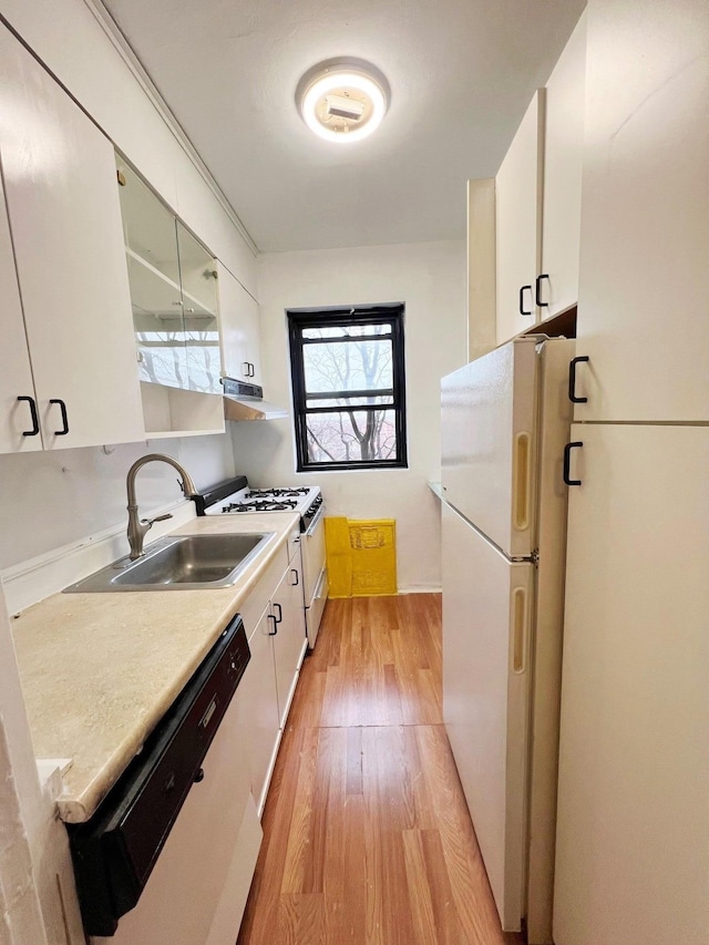 kitchen with white appliances, range hood, white cabinets, sink, and light hardwood / wood-style flooring