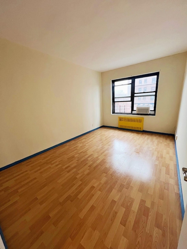 spare room featuring light hardwood / wood-style floors, cooling unit, and radiator heating unit