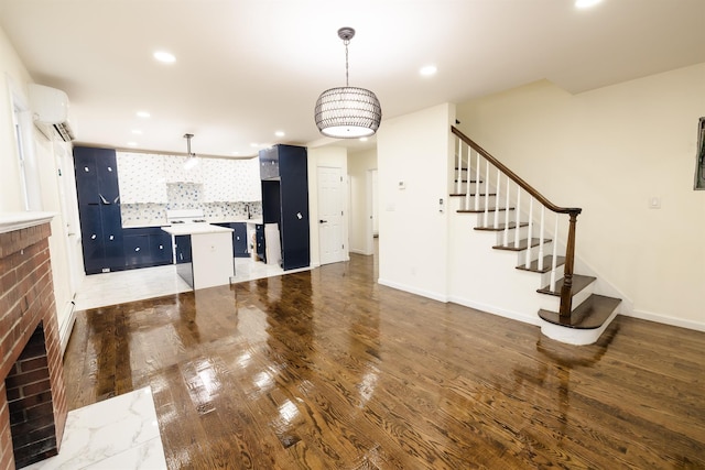 kitchen featuring decorative light fixtures, a wall unit AC, a kitchen island, a kitchen breakfast bar, and dark hardwood / wood-style flooring