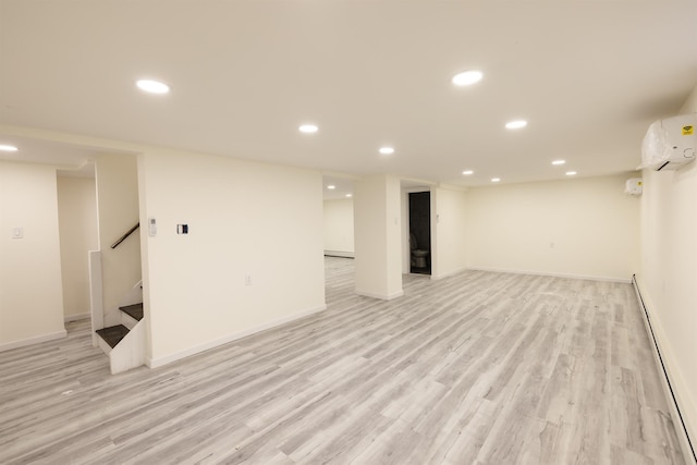 basement featuring a baseboard radiator, light hardwood / wood-style floors, and a wall mounted air conditioner