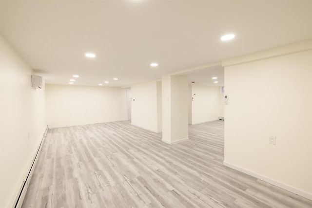 basement with light wood-type flooring and a baseboard heating unit