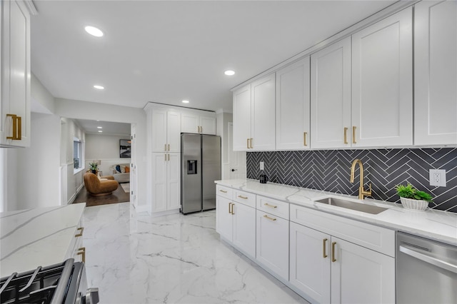 kitchen with sink, appliances with stainless steel finishes, light stone counters, white cabinets, and decorative backsplash