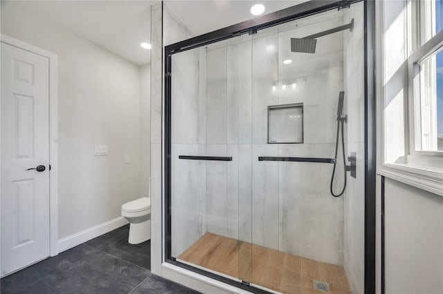 bathroom with a wealth of natural light, a shower with door, and toilet