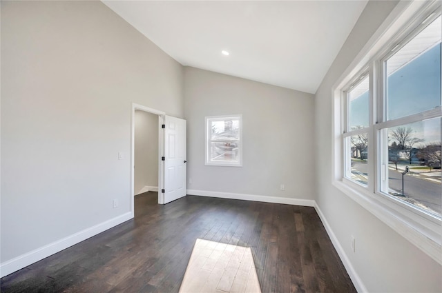 spare room with dark wood-type flooring and lofted ceiling