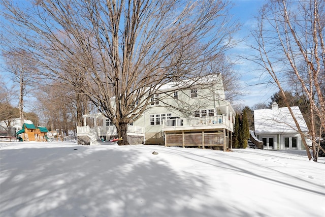 yard covered in snow featuring a playground and a deck