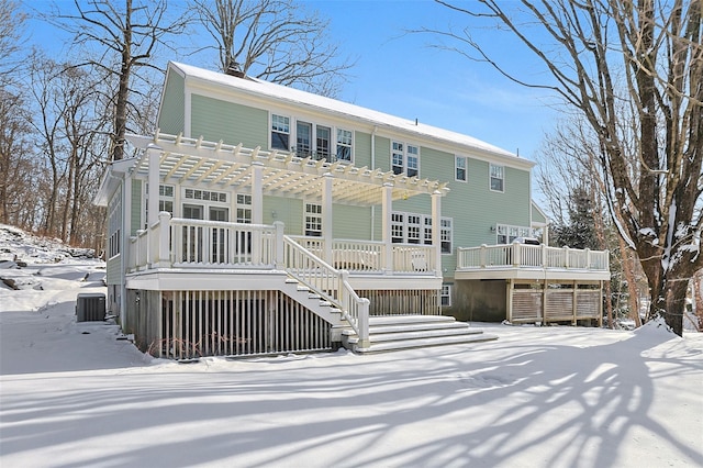 snow covered rear of property with a pergola and a deck