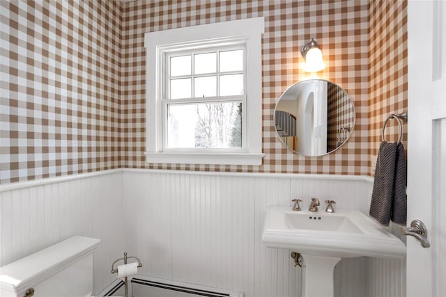 bathroom with baseboard heating, wooden walls, and toilet