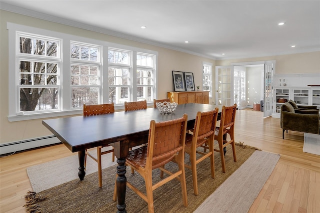 dining room featuring a baseboard radiator, ornamental molding, and light hardwood / wood-style flooring