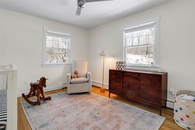 living area with baseboard heating and light hardwood / wood-style floors