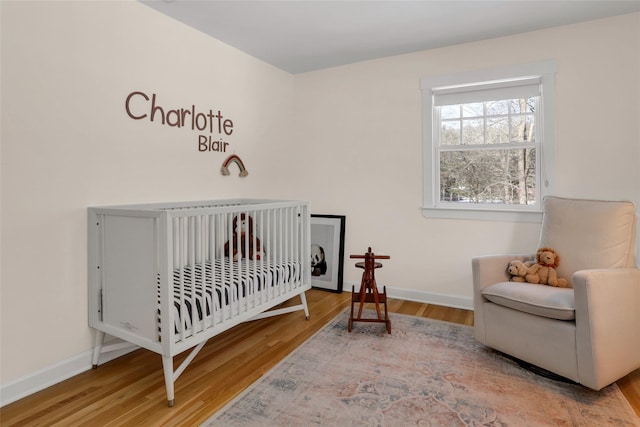 bedroom with a crib and wood-type flooring