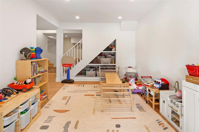 rec room with built in shelves and light hardwood / wood-style flooring