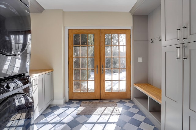 laundry area with cabinets, stacked washing maching and dryer, and french doors