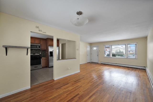 unfurnished living room featuring baseboard heating and light hardwood / wood-style flooring