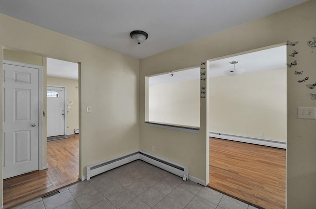 unfurnished room featuring a baseboard heating unit and light tile patterned flooring