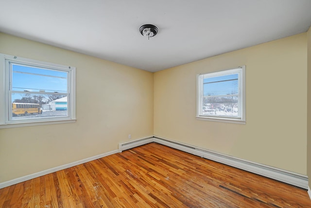 empty room featuring plenty of natural light, a baseboard radiator, and hardwood / wood-style floors