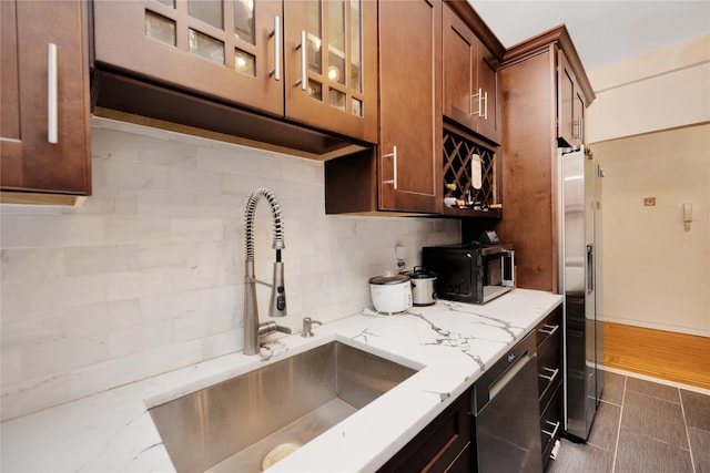 kitchen with sink, backsplash, light stone counters, and appliances with stainless steel finishes