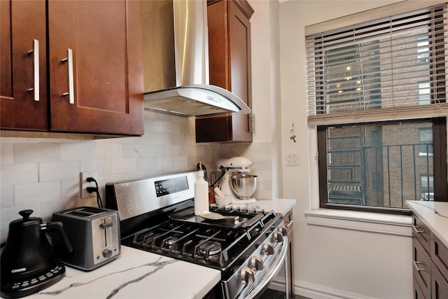 kitchen with exhaust hood, light stone countertops, gas range, and tasteful backsplash