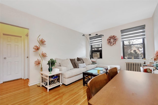 living room with radiator heating unit, light hardwood / wood-style floors, and cooling unit