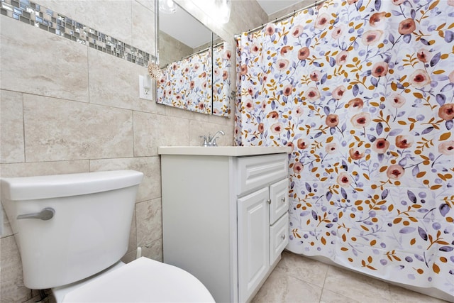 bathroom with tile walls, toilet, vanity, and tile patterned flooring