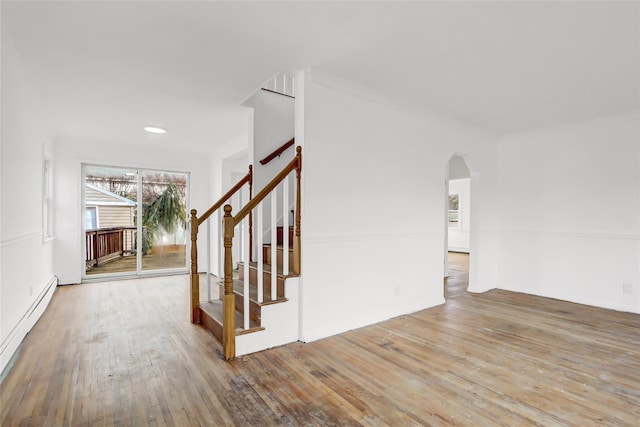 stairs featuring a baseboard radiator, ornamental molding, and hardwood / wood-style floors