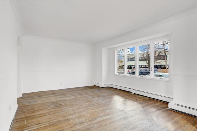 empty room with wood-type flooring, crown molding, and a baseboard radiator