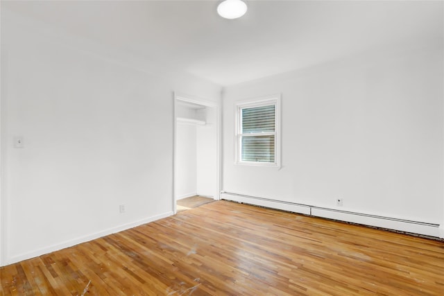 unfurnished room with light hardwood / wood-style floors and a baseboard heating unit