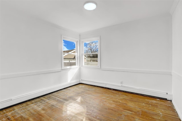 empty room with wood-type flooring and a baseboard heating unit