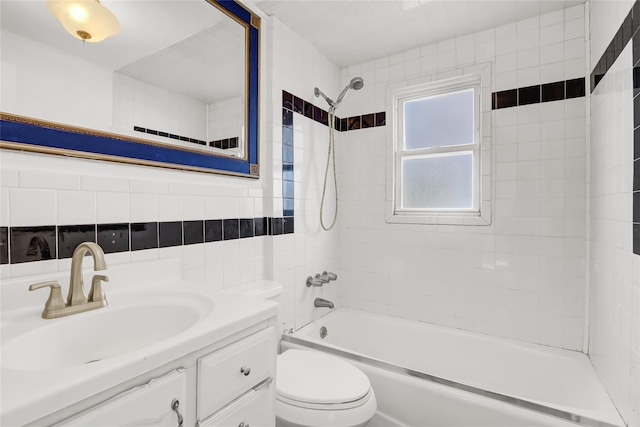 full bathroom with tiled shower / bath, tasteful backsplash, tile walls, vanity, and toilet